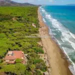 Aerial view showing beach house, forest, beach and sea